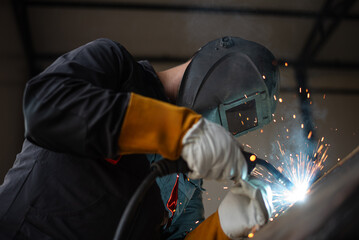 Industrial worker welding metal and making sparks