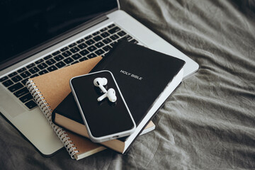 Bible, laptop and earphones on grey bed background, Bible study and worship.