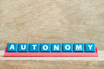 Obraz premium Tile alphabet letter with word autonomy in red color rack on wood background