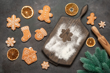 Culinary background with christmas gingerbread cookies, wooden cutting board, fir branch, dried orange slices, dark background, top view, flat lay, copy space.