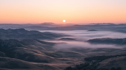 Mountain landscape at sunrise with mist rolling over hills creating a serene and picturesque morning view