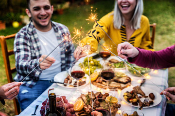 Happy family celebrating with fireworks at barbecue backyard party - Young people having fun with...