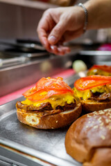 Close-up of a hand placing a tomato slice on a cheeseburger, highlighting the vibrant layers of ingredients. Perfect for culinary, food photography, or fast-food themes