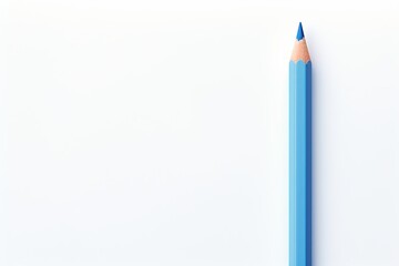 A blue colored pencil rests on a blank white surface in a well-lit workspace setting