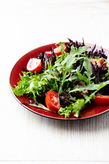 Salad with fresh tomatoes and arugula on a bright stone background. Close up. Copy space.