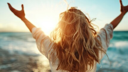 A serene woman stands on the beach with open arms, embracing the sunrise over the ocean, evoking a sense of peace and freedom in the natural setting.