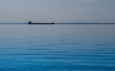 A long barge in the sea on the horizon.