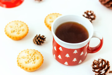 red mug with white fir trees and cakes with snowflake and pine cone