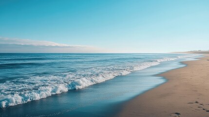 Obraz premium Wide canvas captures the serene beauty of expansive ocean blues, with impending white waves approaching a sandy shore, offering excellent photo style copy space for design.