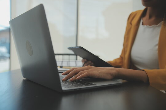 Close up Business woman using calculator and laptop for do math finance on wooden desk, tax, accounting, statistics and analytical research concept