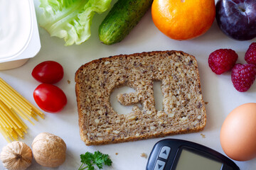 Slice of whole grain bread with symbol GI cut out, glucometer and products with low glycemic index, creative concept