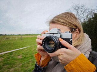 Frau hält analoge alte Kamera in der Hand und fotografiert