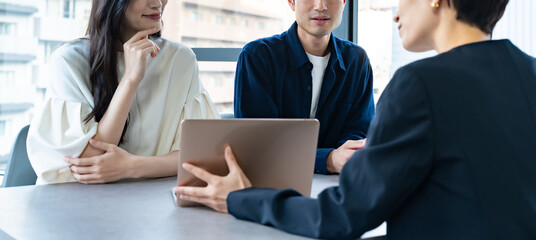 説明をするスーツを着た女性と話を聞くカップル