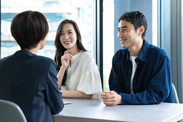 説明をするスーツを着た女性と話を聞くカップル