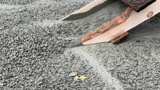 A cement mixer is pouring concrete into a wooden ramp. The ramp is being built for a construction project