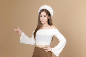 Young Asian beauty woman long hair with beret lovely face and perfect clean skin on isolated beige background. Female model pointing finger, Facial treatment, Cosmetology, plastic surgery.