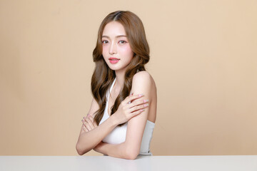 Naklejka premium Young Asian beauty woman curly long hair with korean makeup style touch her face and perfect skin on isolated beige background. Facial treatment, Cosmetology, plastic surgery.