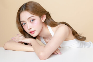 Obraz premium Young Asian beauty woman curly long hair with korean makeup style touch her face and perfect skin on isolated beige background. Facial treatment, Cosmetology, plastic surgery.