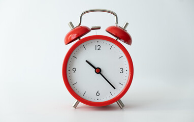 The classic red alarm clock is isolated on a white background