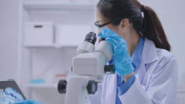 Asian Researcher using a microscope in the clinical lab.Female Researcher working in the clinical laboratory,Medical or scientific researcher or Asian woman doctor looking at professional microscope.