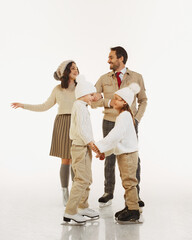 Happy family, parents and children, dressed in cozy winter clothing, smiling and enjoying day out ice skating. Bonding family moment. Concept of winter, vacation, holiday, leisure activity