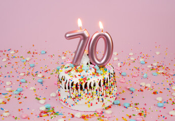 Birthday cake with burning candles on pink background. Number 70.