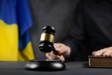 Justice and court concept in Ukraine. Judge hold gavel and law book on a flag background