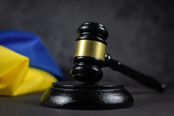 Judge gavel and flag of Ukraine on dark background. Blue yellow Ukrainian flag and wooden judge...