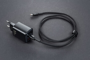 Black smartphone charger on dark background. Charger and USB cable type C on dark background