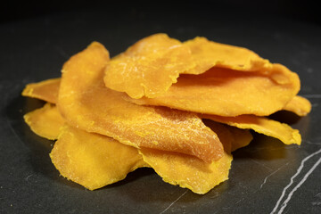 Heap of dried mango slices on dark background