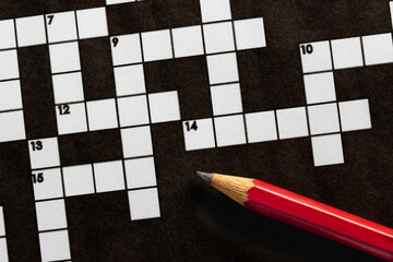 Empty, unfinished crossword puzzle, black and white crossword puzzle with a red pencil. On black...