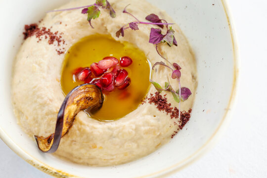 A bowl of Baba Ghanouj with herbs and pomegranate.