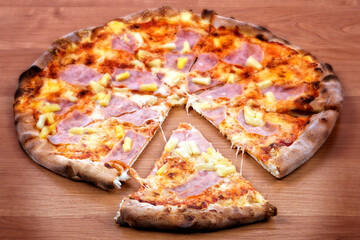 Hawaiian pizza with a slice on the wooden table