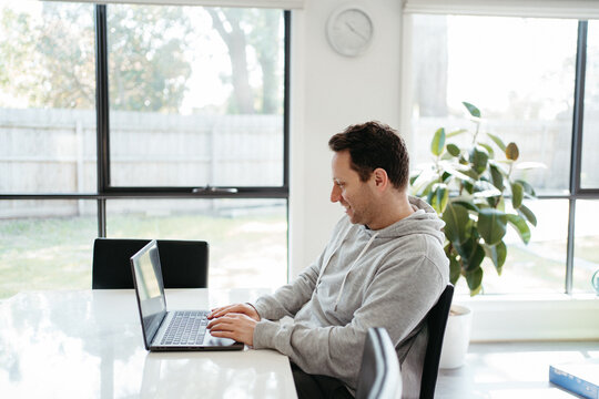 Middle-aged man working on his laptop on the dining table.