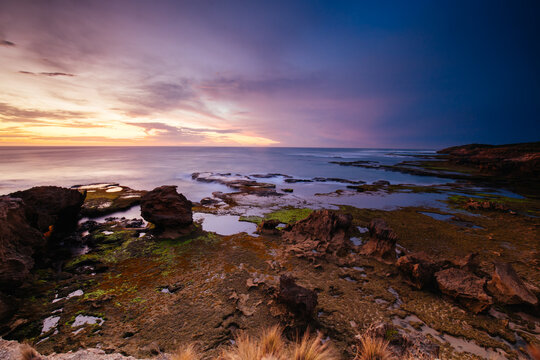 The idyllic Pearses Beach and headland around Pirates Bay Cove on a hot summer's evening.