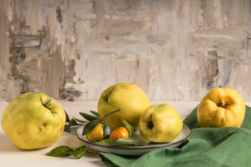 Fresh quince and tangerines on a plate on the table. Selective focus. Autumn fruit harvest.