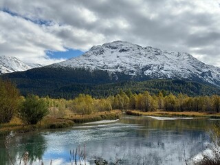 Serene landscape with snow-capped mountains reflected in a tranquil lake in Samedan, Switzerland