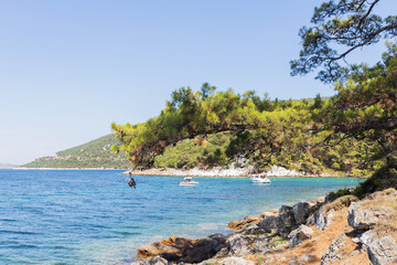 Obraz premium Boats near rocky shore surrounded by pine trees and clear blue waters