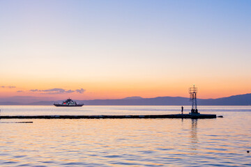 Ferry boat sails across the tranquil waters during a picturesque sunset.