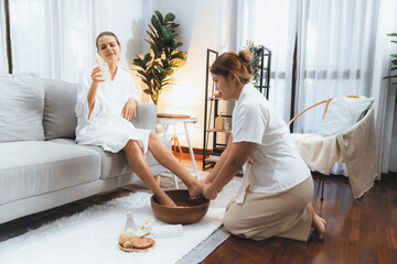 Woman indulges in blissful foot massage at luxurious spa salon while masseur give reflexology therapy in gentle day light ambiance resort or hotel foot spa. Quiescent