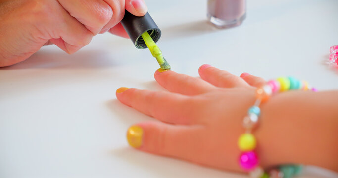 Mother Painting Daughter's Nails with Bright Green Polish