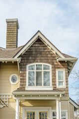 Top of grey stucco luxury house with shingle roof, red and yellow trees and nice windows in Summer in Vancouver, Canada, North America. Day time on June 2024.