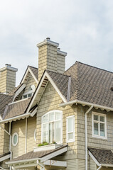 Obraz premium Top of grey stucco luxury house with shingle roof, red and yellow trees and nice windows in Summer in Vancouver, Canada, North America. Day time on June 2024.