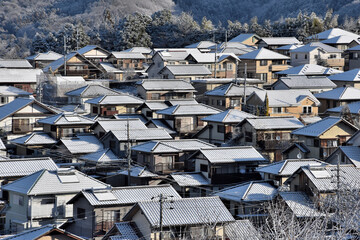 丘の上の住宅の屋根に積もった雪