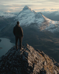 man standing on mountain peak with stunning view of snowy mountains in the distance