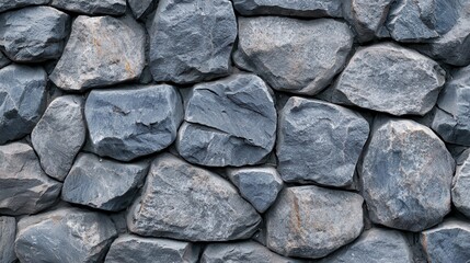 Fototapeta premium Textured gray stone wall featuring various shapes and sizes of rocks.