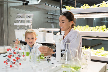 Teacher and little child boy scientists learning science and doing analysis together in laboratory. Student and teacher learning science in classroom. Science and education concept