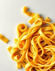 A pile of yellow, fresh pasta noodles sits on a white surface, ready to be cooked