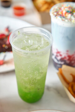 Close-up shot of a green soda with sweet treats on the side
