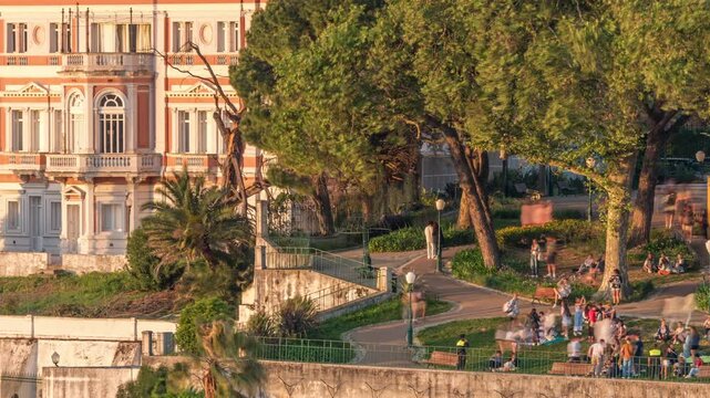 Jardim do Torel timelapse, a traditional garden and viewpoint with unusual views to the city center of Lisbon during evening. People watching sunset sitting on a lawn of terrace. Portugal